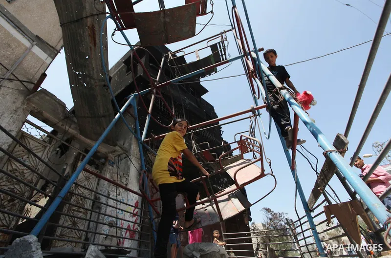 Palestinian children play near a damaged mini ferris wheel in the wartorn Shejaiya district of Gaza City on July 28, 2014 on the first day of Eid al-Fitr holiday. The Muslim three-day Eid al-Fitr festival, that marks the...