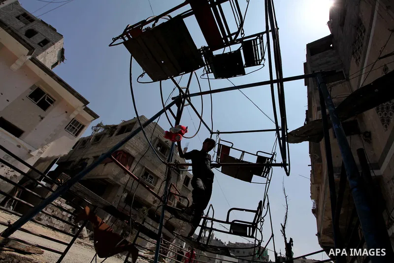 Palestinian children play near a damaged mini ferris wheel in the wartorn Shejaiya district of Gaza City on July 28, 2014 on the first day of Eid al-Fitr holiday. The Muslim three-day Eid al-Fitr festival, that marks the...