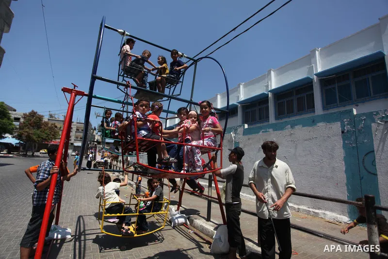 Palestinian children play on a mini ferris wheel outside an United Nations (UN) school in Jabalia in the northern Gaza strip, on July 28, 2014, on the beginning of the Muslim Eid festival ending the month-long fast of Ra...