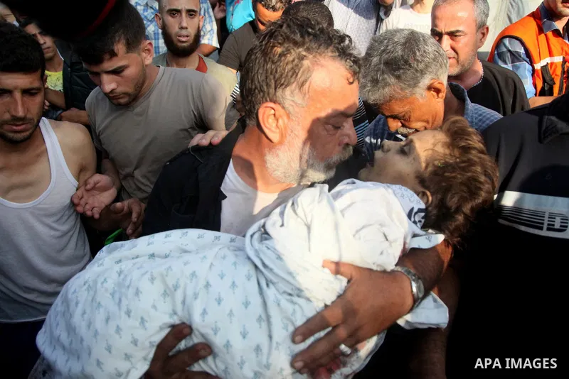 Akram Mogdadm holds the body of his son, Baraa, 6, who was killed along with 9 other people, all but one of them children, in an explosion at park at Shati refugee camp, in Gaza, in the northern Gaza City on July 28, 201...