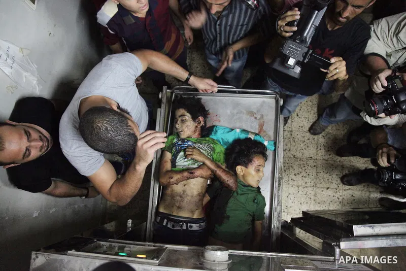 Palestinian men mourn over the bodies of six children who were killed in a explosion in a public playground in the beachfront Shati refugee camp in Gaza City on July 28, 2014. At least 10 Palestinians are killed and more...