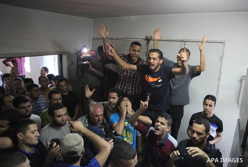 Palestinian men mourn over the bodies of six children who were killed in a explosion in a public playground in the beachfront Shati refugee camp in Gaza City on July 28, 2014. At least 10 Palestinians are killed and more...