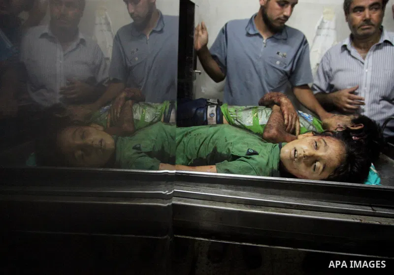 Palestinian men mourn over the bodies of six children who were killed in a explosion in a public playground in the beachfront Shati refugee camp in Gaza City on July 28, 2014. At least 10 Palestinians are killed and more...