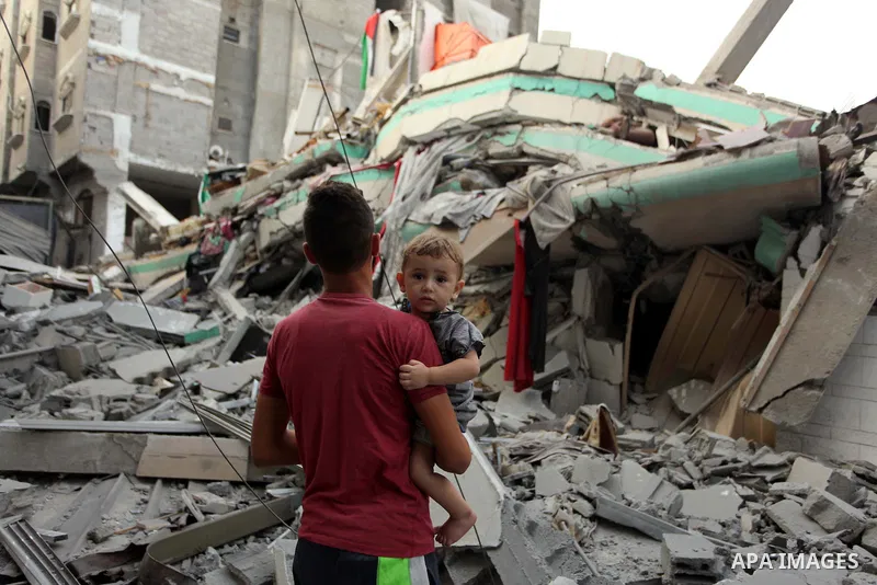 A Palestinian man carrying a child looks at the destroyed house of Hamas top leader in Gaza, Ismail Haniya, after it was hit by an overnight Israeli air strike, on July 29, 2014 in Gaza City. Bloodshed in and around Gaza...