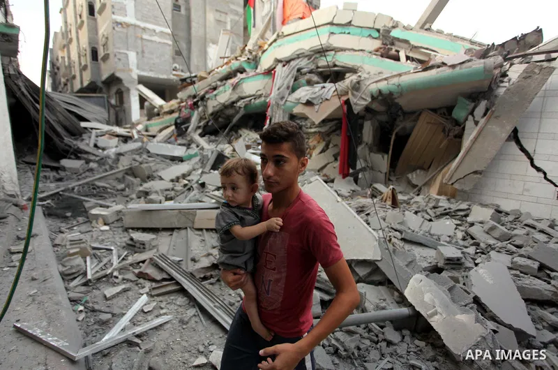 A Palestinian man carrying a child looks at the destroyed house of Hamas top leader in Gaza, Ismail Haniya, after it was hit by an overnight Israeli air strike, on July 29, 2014 in Gaza City. Bloodshed in and around Gaza...