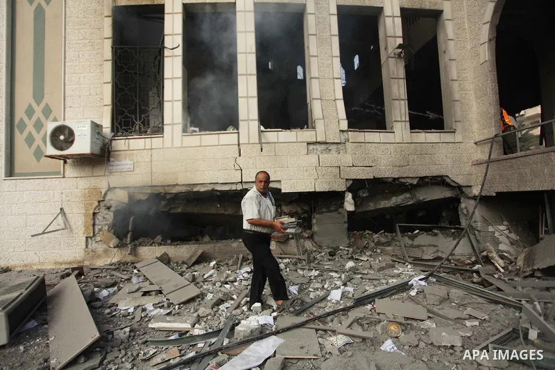A Palestinian man holds copies of the Koran, Islam's holy book, as he inspects the rubble of a destroyed mosque hit by an Israeli air strike, on July 29, 2014, in Gaza City. Bloodshed in and around Gaza surged with strik...