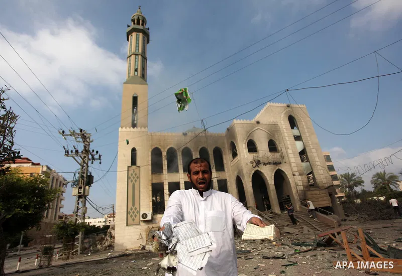 A Palestinian man holds copies of the Koran, Islam's holy book, as he inspects the rubble of a destroyed mosque hit by an Israeli air strike, on July 29, 2014, in Gaza City. Bloodshed in and around Gaza surged with strik...