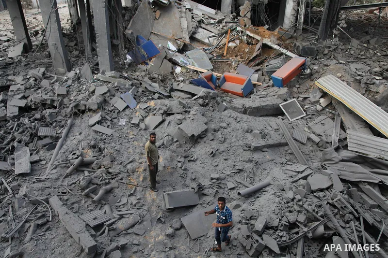 Palestinian neighbours of the Al Aqsa television station dig through rubble after the building was destroyed in an Israeli strike in central Gaza City on July 29, 2014. Following two nights without air strikes, the viole...
