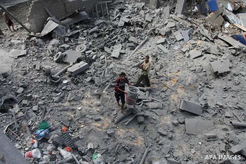 Palestinian neighbours of the Al Aqsa television station dig through rubble after the building was destroyed in an Israeli strike in central Gaza City on July 29, 2014. Following two nights without air strikes, the viole...