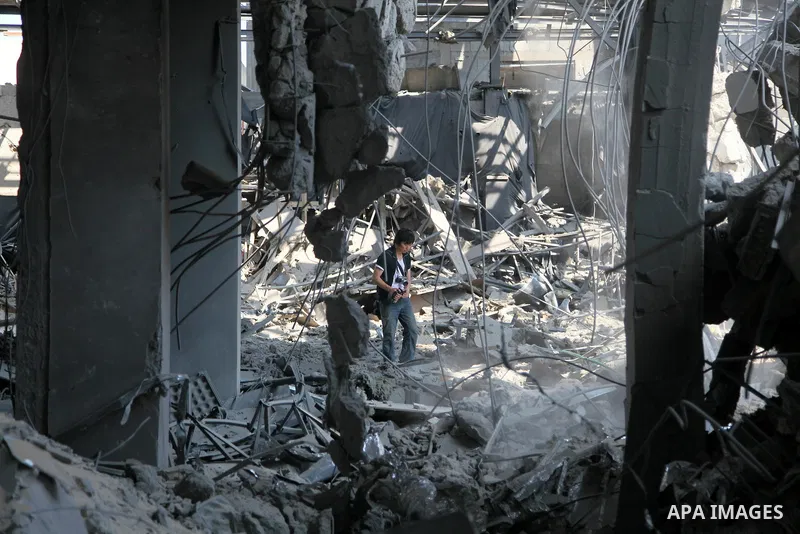 A foreign journalist walks through the rubble of the Al Aqsa television building after it was destroyed in an Israeli strike in central Gaza City on July 29, 2014. Following two nights without air strikes, the violence r...