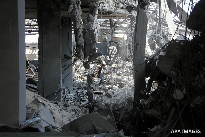 A foreign journalist walks through the rubble of the Al Aqsa television building after it was destroyed in an Israeli strike in central Gaza City on July 29, 2014. Following two nights without air strikes, the violence r...