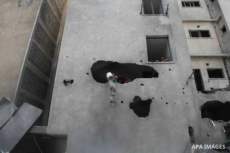 Palestinian neighbours of the Al Aqsa television station dig through rubble after the building was destroyed in an Israeli strike in central Gaza City on July 29, 2014. Following two nights without air strikes, the viole...