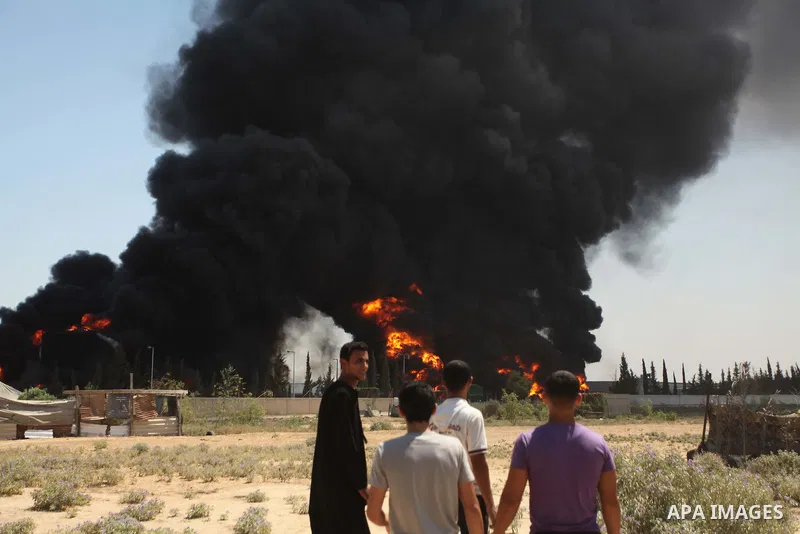 Palestinian men stand looking as flames engulf the fuel tanks of the only power plant supplying electricity to the Gaza Strip after it was hit by overnight Israeli shelling, on July 29, 2014, in the south of Gaza City. T...