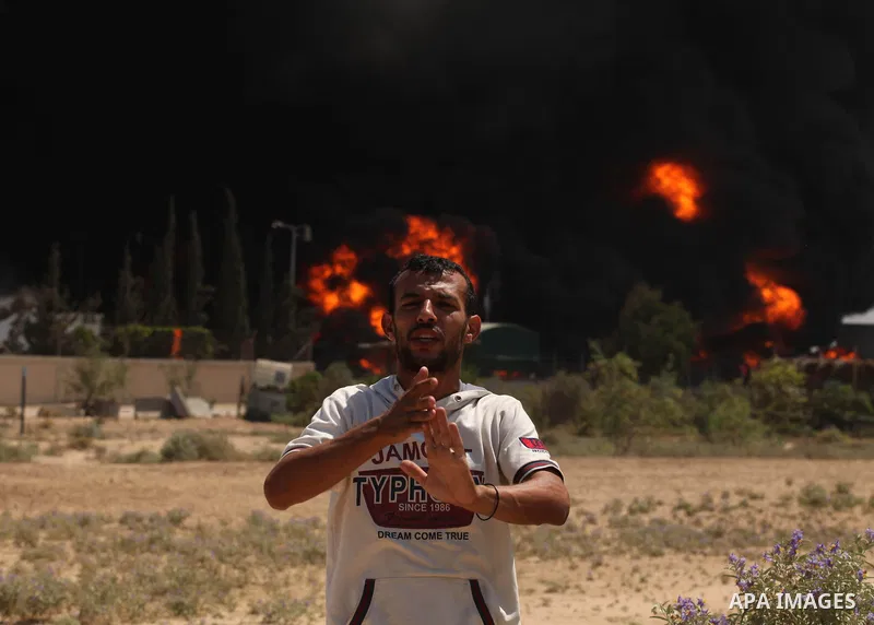 Palestinian men stand looking as flames engulf the fuel tanks of the only power plant supplying electricity to the Gaza Strip after it was hit by overnight Israeli shelling, on July 29, 2014, in the south of Gaza City. T...