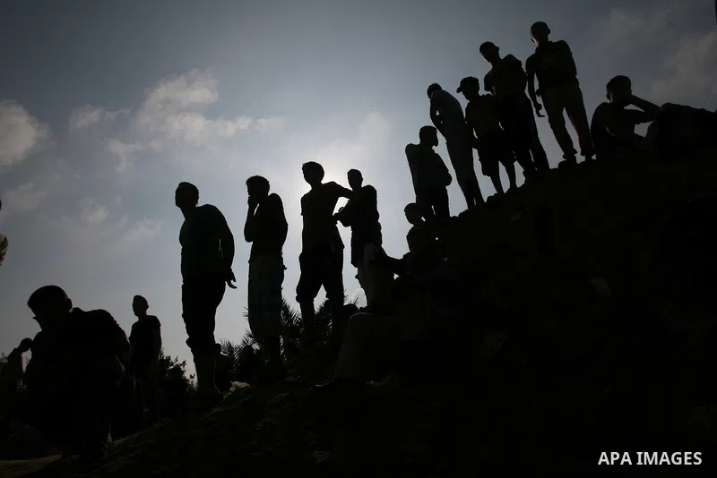 Palestinians look at rescue workers as they search for victims under the rubble of a house, which witnesses said was destroyed in an Israeli air strike, in Rafah in the southern Gaza Strip July 29, 2014. Israel's militar...
