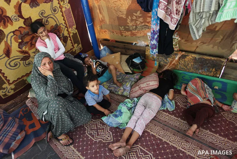 Palestinians sit at a UN school at the Jabalia refugee camp in the northern Gaza Strip after the area was hit by Israeli shelling on July 30, 2014. Israeli bombardments early on July 30 killed "dozens" of Palestinians in...