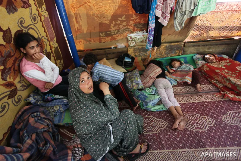 Palestinians sit at a UN school at the Jabalia refugee camp in the northern Gaza Strip after the area was hit by Israeli shelling on July 30, 2014. Israeli bombardments early on July 30 killed "dozens" of Palestinians in...