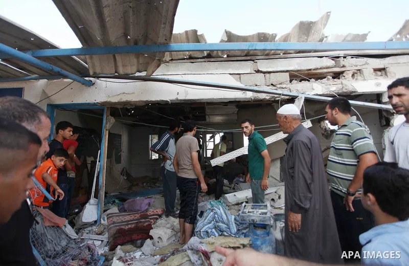 Palestinian men inspect the damage at a UN school at the Jabalia refugee camp in the northern Gaza Strip after the area was hit by Israeli shelling on July 30, 2014. Israeli bombardments early on July 30 killed "dozens"...