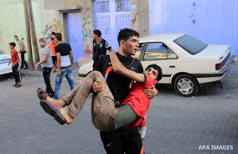 Palestinians help carry injured men following an Israeli Strike in Shijaiyah neighborhood, eastern Gaza City, Wednesday, July 30, 2014. Photo by Omar Abed