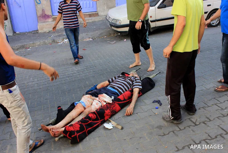 Palestinians help carry injured men following an Israeli Strike in Shijaiyah neighborhood, eastern Gaza City, Wednesday, July 30, 2014. Photo by Omar Abed