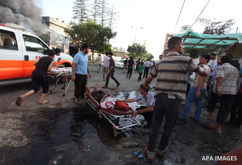 Palestinian paramedics move a victim of an Israeli air strike on a market place to an ambulance in the Shejaiya neighbourhood near Gaza City on July 30, 2014. At least 15 people were killed and 200 people wounded in an I...