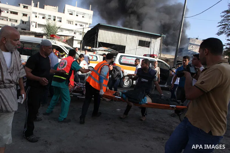 Palestinian paramedics move a victim of an Israeli air strike on a market place to an ambulance in the Shejaiya neighbourhood near Gaza City on July 30, 2014. At least 15 people were killed and 200 people wounded in an I...