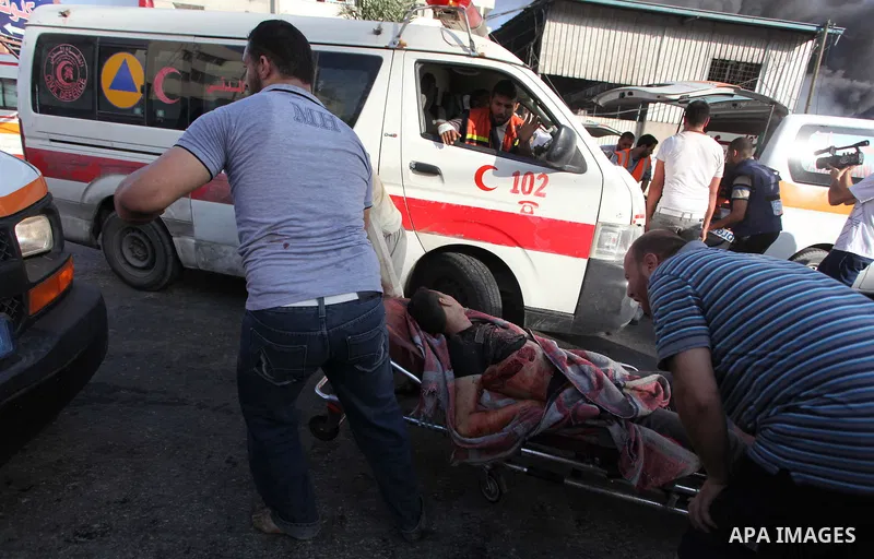 Palestinian paramedics move a victim of an Israeli air strike on a market place to an ambulance in the Shejaiya neighbourhood near Gaza City on July 30, 2014. At least 15 people were killed and 200 people wounded in an I...