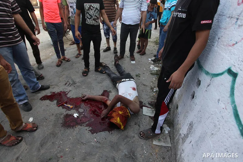 Palestinian paramedics move a victim of an Israeli air strike on a market place to an ambulance in the Shejaiya neighbourhood near Gaza City on July 30, 2014. At least 15 people were killed and 200 people wounded in an I...