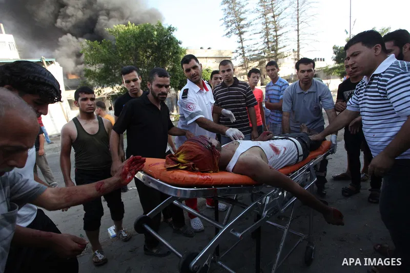 Palestinian paramedics move a victim of an Israeli air strike on a market place to an ambulance in the Shejaiya neighbourhood near Gaza City on July 30, 2014. At least 15 people were killed and 200 people wounded in an I...