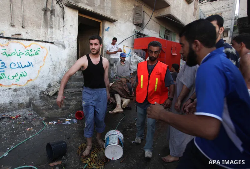Palestinian paramedics move a victim of an Israeli air strike on a market place to an ambulance in the Shejaiya neighbourhood near Gaza City on July 30, 2014. At least 15 people were killed and 200 people wounded in an I...