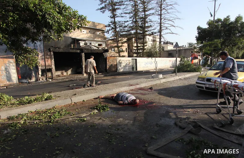 Palestinian paramedics move a victim of an Israeli air strike on a market place to an ambulance in the Shejaiya neighbourhood near Gaza City on July 30, 2014. At least 15 people were killed and 200 people wounded in an I...