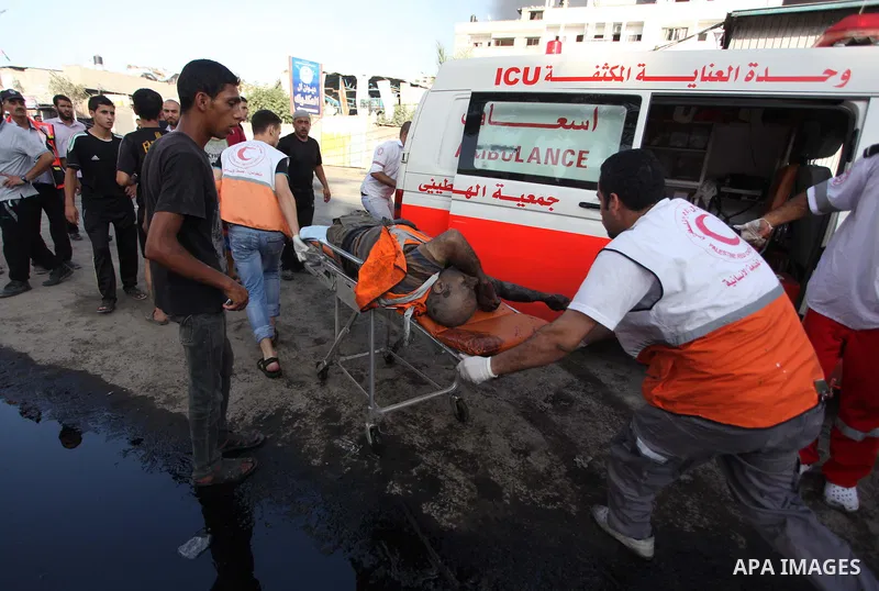 Palestinian paramedics move a victim of an Israeli air strike on a market place to an ambulance in the Shejaiya neighbourhood near Gaza City on July 30, 2014. At least 15 people were killed and 200 people wounded in an I...