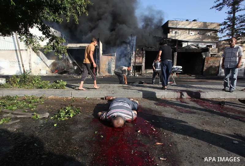 Palestinian paramedics move a victim of an Israeli air strike on a market place to an ambulance in the Shejaiya neighbourhood near Gaza City on July 30, 2014. At least 15 people were killed and 200 people wounded in an I...