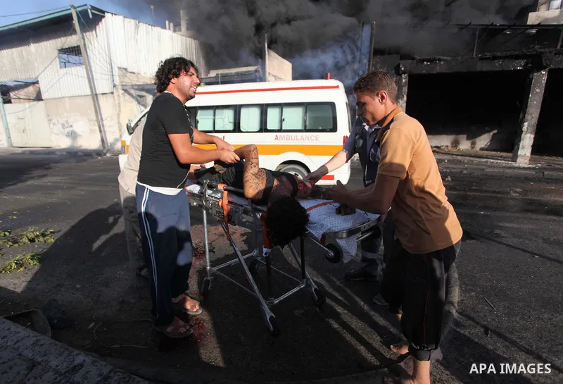 Palestinian paramedics move a victim of an Israeli air strike on a market place to an ambulance in the Shejaiya neighbourhood near Gaza City on July 30, 2014. At least 15 people were killed and 200 people wounded in an I...