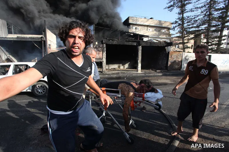Palestinian paramedics move a victim of an Israeli air strike on a market place to an ambulance in the Shejaiya neighbourhood near Gaza City on July 30, 2014. At least 15 people were killed and 200 people wounded in an I...