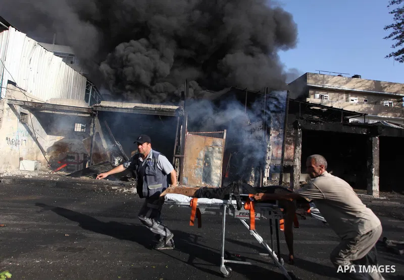 Palestinian paramedics move a victim of an Israeli air strike on a market place to an ambulance in the Shejaiya neighbourhood near Gaza City on July 30, 2014. At least 15 people were killed and 200 people wounded in an I...