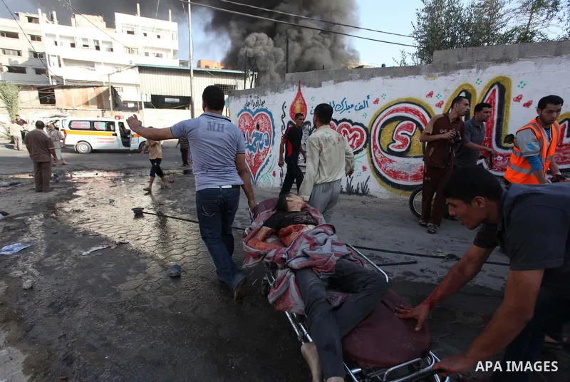 Palestinian paramedics move a victim of an Israeli air strike on a market place to an ambulance in the Shejaiya neighbourhood near Gaza City on July 30, 2014. At least 15 people were killed and 200 people wounded in an I...