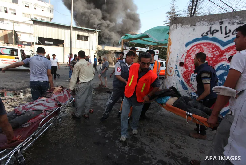 Palestinian paramedics move a victim of an Israeli air strike on a market place to an ambulance in the Shejaiya neighbourhood near Gaza City on July 30, 2014. At least 15 people were killed and 200 people wounded in an I...