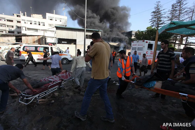 Palestinian paramedics move a victim of an Israeli air strike on a market place to an ambulance in the Shejaiya neighbourhood near Gaza City on July 30, 2014. At least 15 people were killed and 200 people wounded in an I...