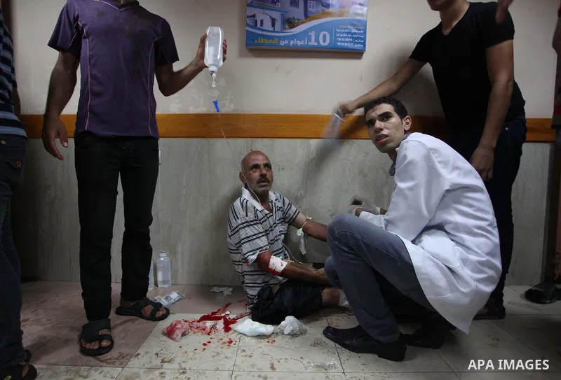Palestinian medics wheel a wounded man, following an Israeli Strike in Shijaiyah neighborhood, to the emergency room of the Shifa Hospital, in Gaza City, Wednesday, July 30, 2014. Photo by Ashraf Amra
