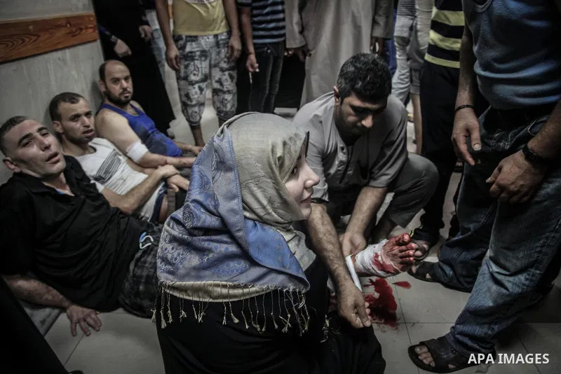 Palestinians wheel a wounded man, injured from an Israeli Strike in Shijaiyah neighborhood, to an emergency room at Shifa Hospital, in Gaza City, Wednesday, July 30, 2014. Photo by Ezz al-Zanoun