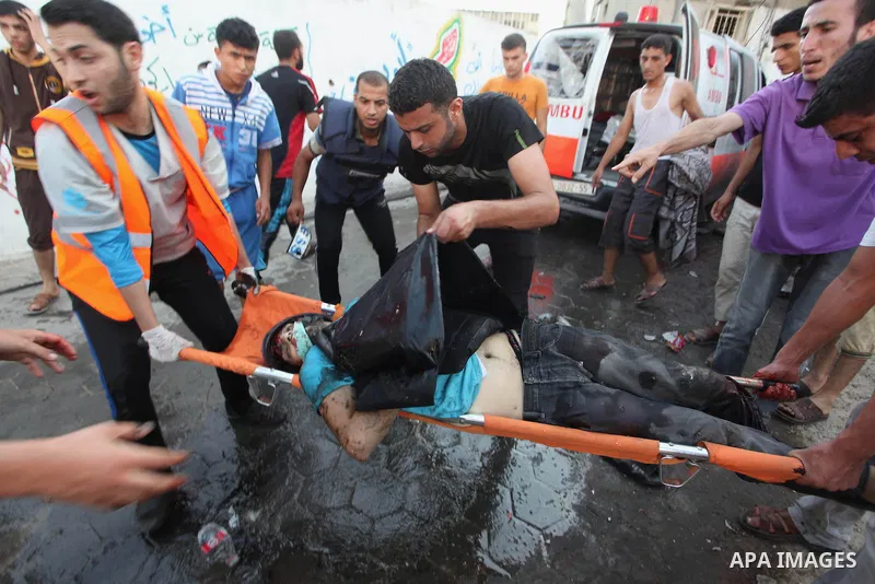 Palestinian men move the body of Palestinian journalist, Rami Rayan, the victim of an Israeli air strike on a market place to an ambulance in the Shejaiya neighbourhood near Gaza City on July 30, 2014. At least 15 people...