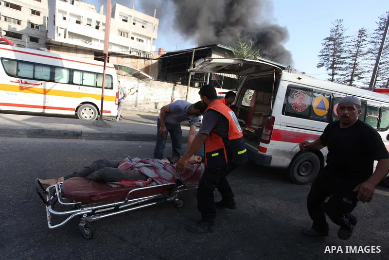 Palestinian paramedics move a victim of an Israeli air strike on a market place to an ambulance in the Shejaiya neighbourhood near Gaza City on July 30, 2014. At least 15 people were killed and 200 people wounded in an I...