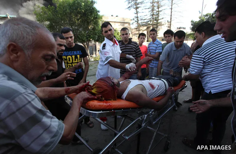 Palestinian paramedics move a victim of an Israeli air strike on a market place to an ambulance in the Shejaiya neighbourhood near Gaza City on July 30, 2014. At least 15 people were killed and 200 people wounded in an I...