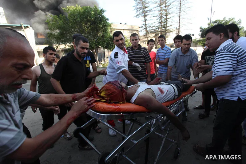 Palestinian paramedics move a victim of an Israeli air strike on a market place to an ambulance in the Shejaiya neighbourhood near Gaza City on July 30, 2014. At least 15 people were killed and 200 people wounded in an I...
