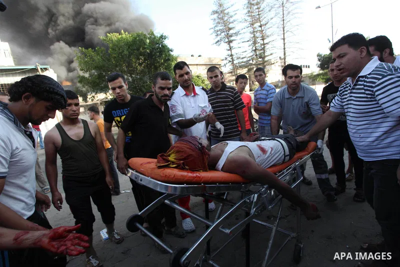 Palestinian paramedics move a victim of an Israeli air strike on a market place to an ambulance in the Shejaiya neighbourhood near Gaza City on July 30, 2014. At least 15 people were killed and 200 people wounded in an I...