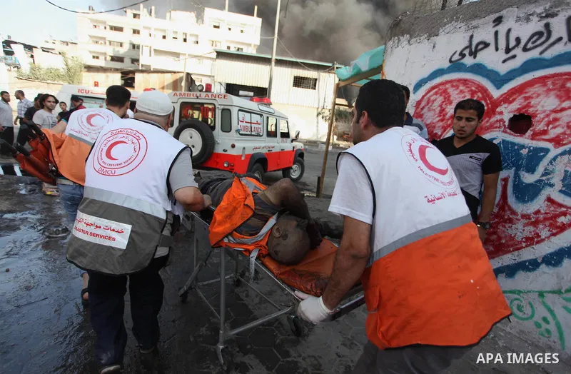 Palestinian paramedics move a victim of an Israeli air strike on a market place to an ambulance in the Shejaiya neighbourhood near Gaza City on July 30, 2014. At least 15 people were killed and 200 people wounded in an I...