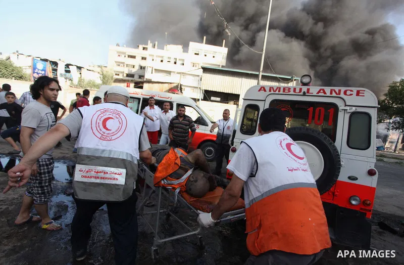 Palestinian paramedics move a victim of an Israeli air strike on a market place to an ambulance in the Shejaiya neighbourhood near Gaza City on July 30, 2014. At least 15 people were killed and 200 people wounded in an I...