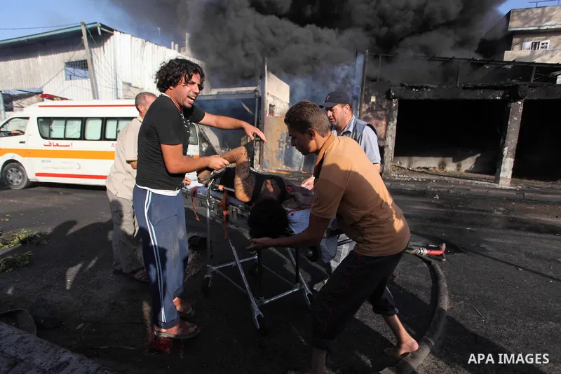 Palestinian paramedics move a victim of an Israeli air strike on a market place to an ambulance in the Shejaiya neighbourhood near Gaza City on July 30, 2014. At least 15 people were killed and 200 people wounded in an I...