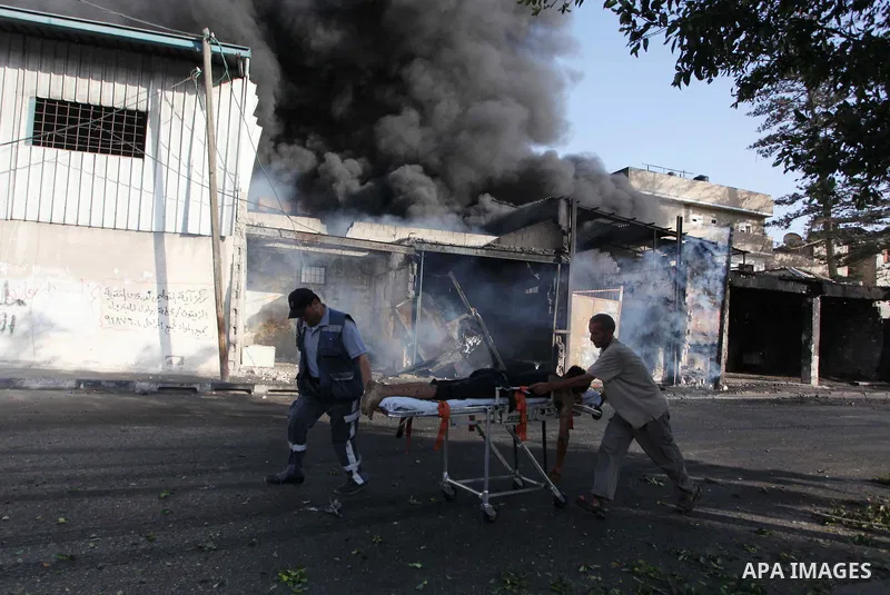 Palestinian paramedics move a victim of an Israeli air strike on a market place to an ambulance in the Shejaiya neighbourhood near Gaza City on July 30, 2014. At least 15 people were killed and 200 people wounded in an I...